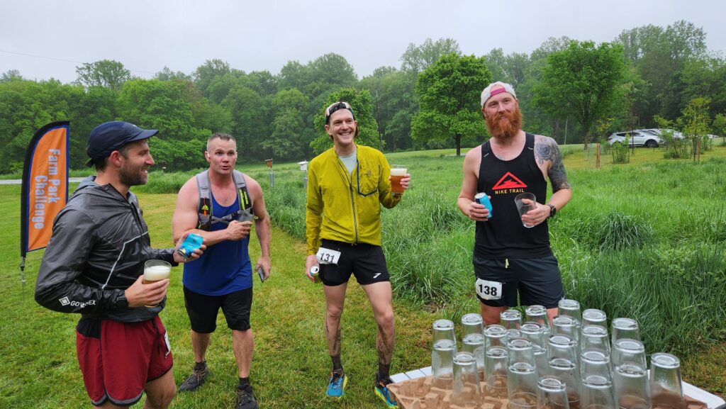 Four men at Farm Park Challenge gathered around the table with the finisher's premium: glasses etched with the logo